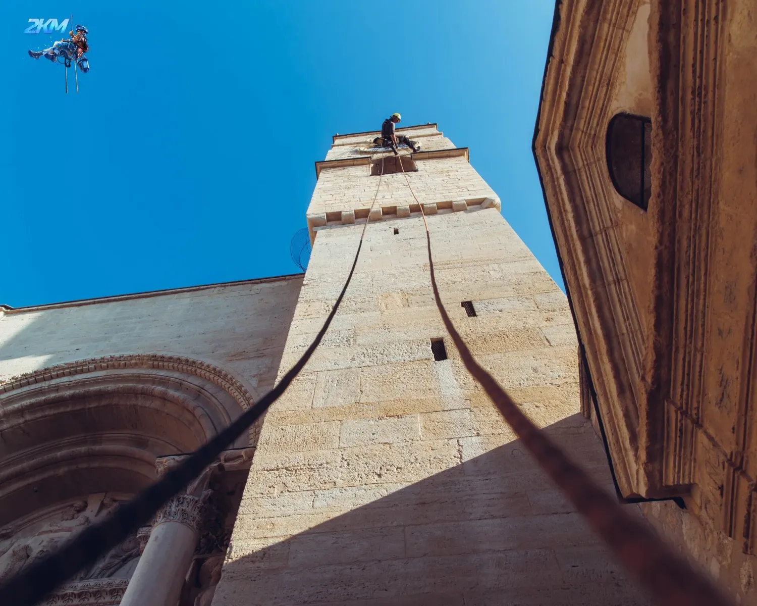 Vue en contre-plongée du clocher de l'abbatiale de Saint-Gilles avec cordes d'accès installées pour l'intervention en hauteur
