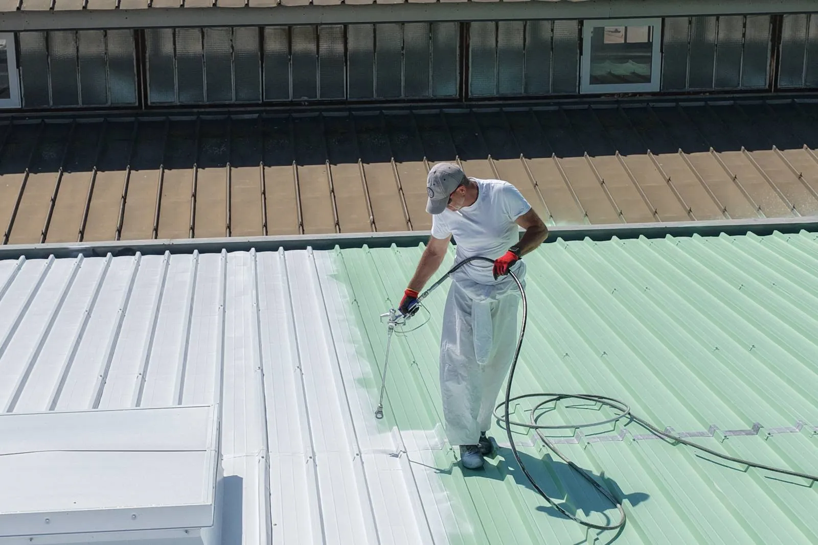 Technicien 2KM pulverisant la peinture Cool Roof reflechissante sur toiture Beziers Box