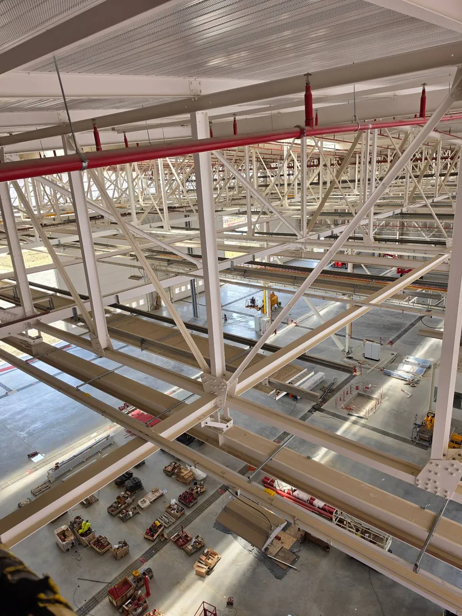 Charpente métallique d'un grand hangar industriel vue en plongée, zone d'intervention des cordistes 2KM