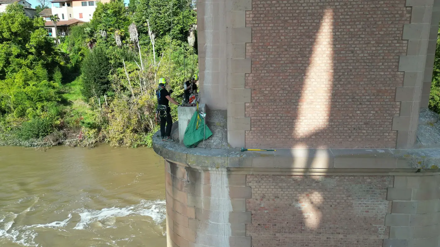Cordiste à côté d'un plot en béton et d'un sac à gravats sur une pile du viaduc ferroviaire d'Albi
