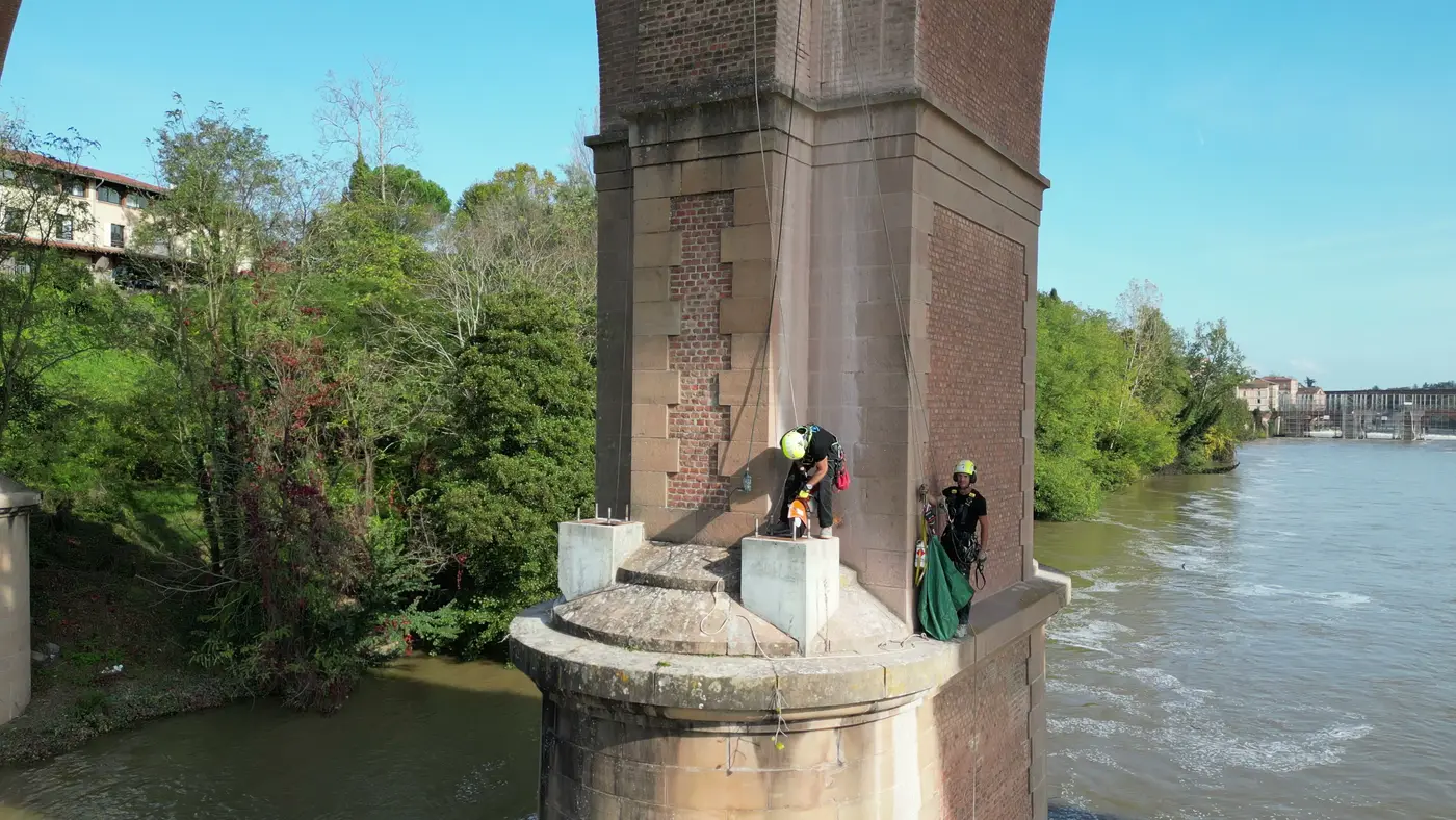 Deux plots en béton sur l'avant-bec d'une pile du viaduc ferroviaire d'Albi, cordistes en place avant la démolition