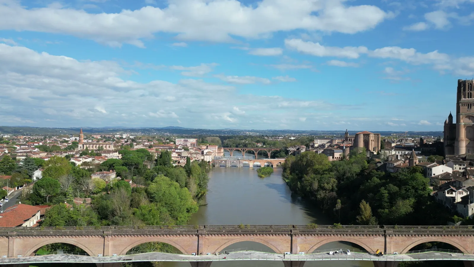 Vue drone du viaduc ferroviaire d'Albi et de sa passerelle piétonne au-dessus du Tarn, cathédrale en arrière-plan