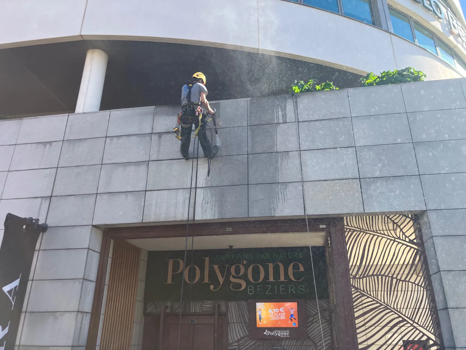 Cordiste 2KM nettoyant la facade du Polygone Beziers au nettoyeur haute pression