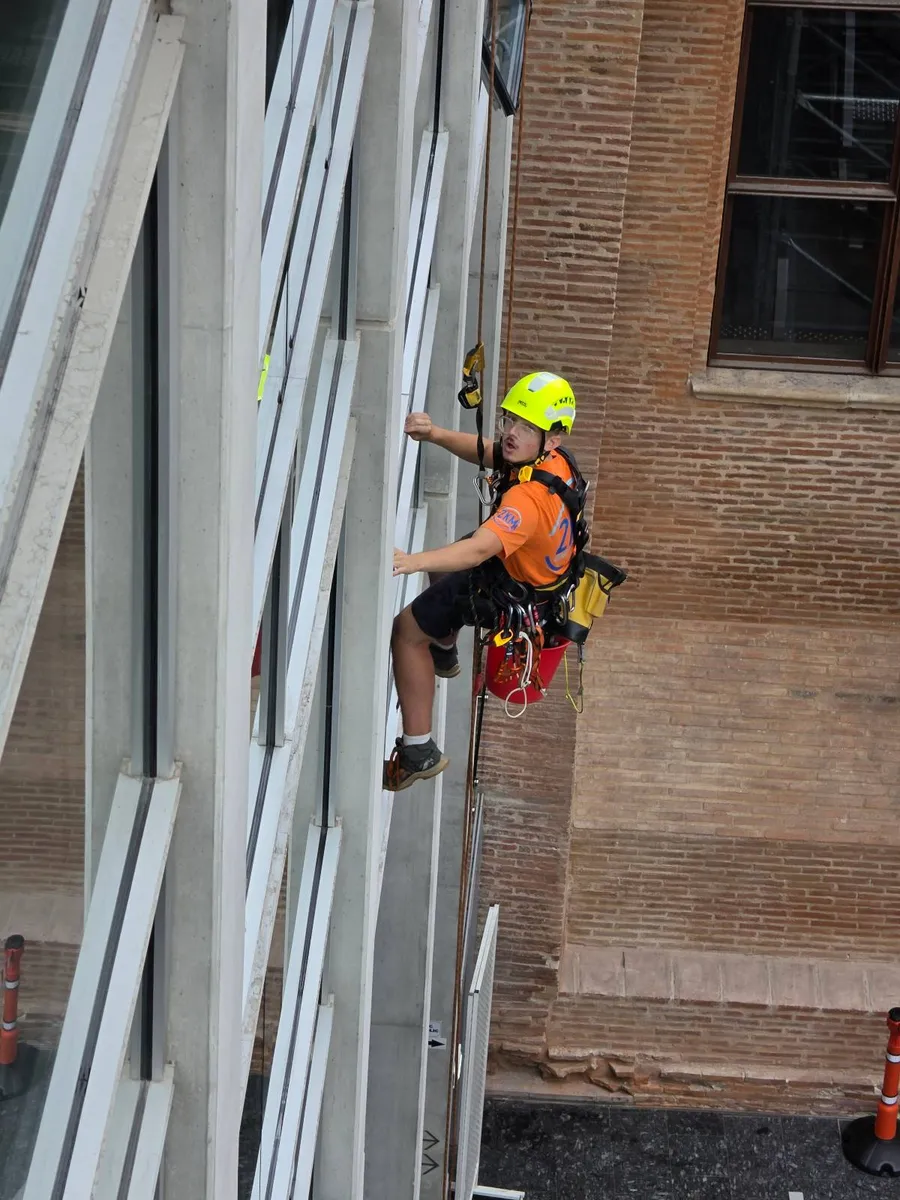 Cordiste suspendu entre une façade vitrée et un mur de brique au palais de justice de Toulouse