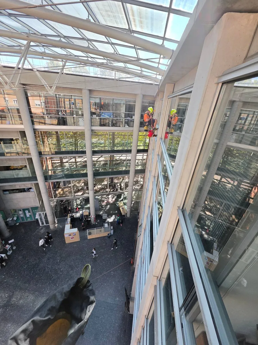 Vue plongeante depuis le haut de l'atrium du Tribunal judiciaire de Toulouse pendant le nettoyage des vitres sur cordes