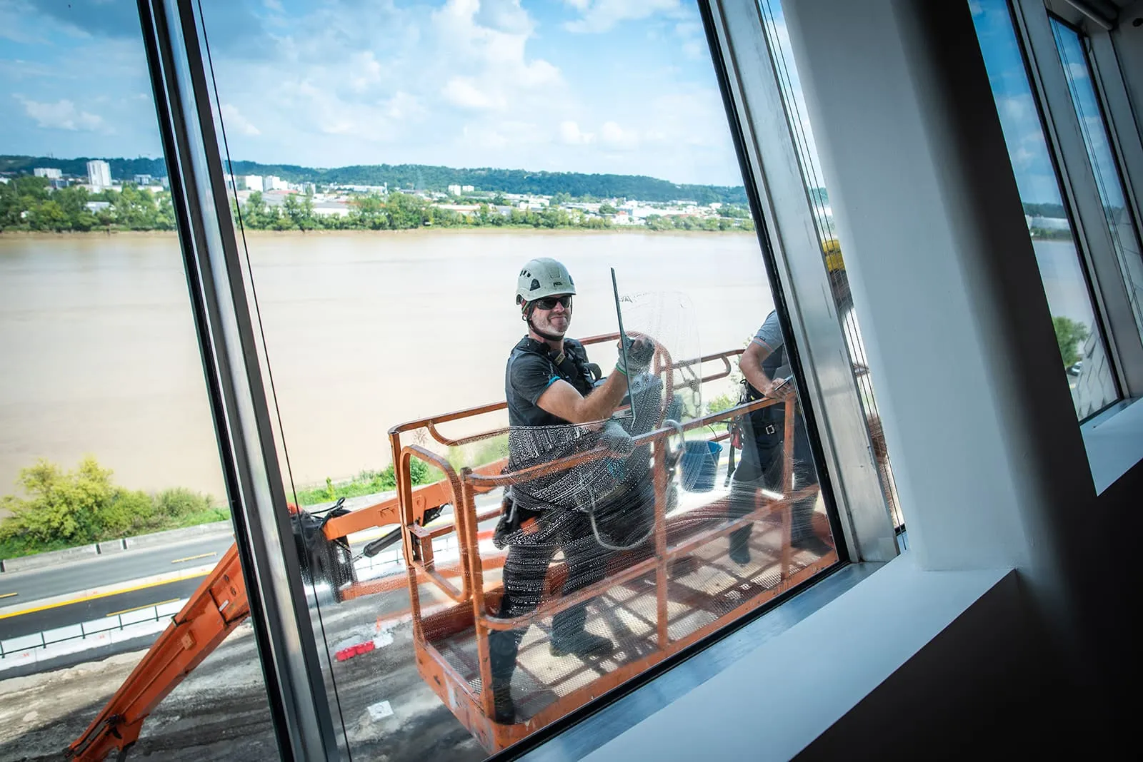 Technicien 2KM en nacelle nettoyant la vitrerie de La Méca avec la Garonne en arrière-plan