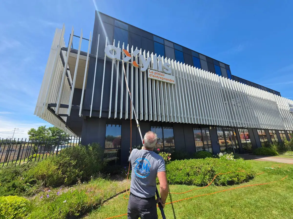 Laveur de vitres 2KM à la perche osmoseur devant l'enseigne Axylis Expertise Comptable à Béziers