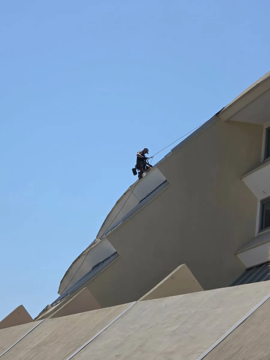 Cordiste 2KM en descente sur corde devant la facade de la residence Heliopolis Cap d'Agde pour Foncia