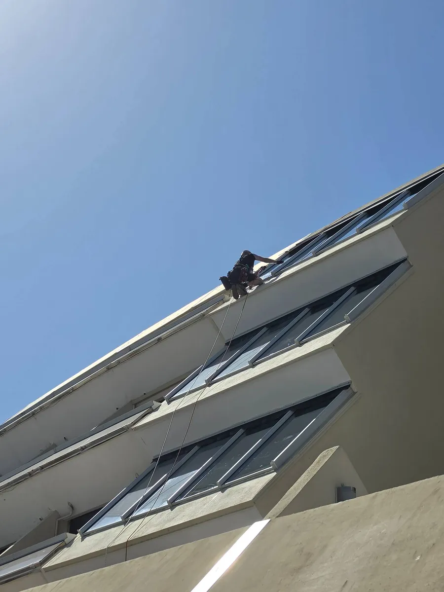 Technicien cordiste 2KM nettoyant les vitres a la raclette mouilleur sur la residence Heliopolis