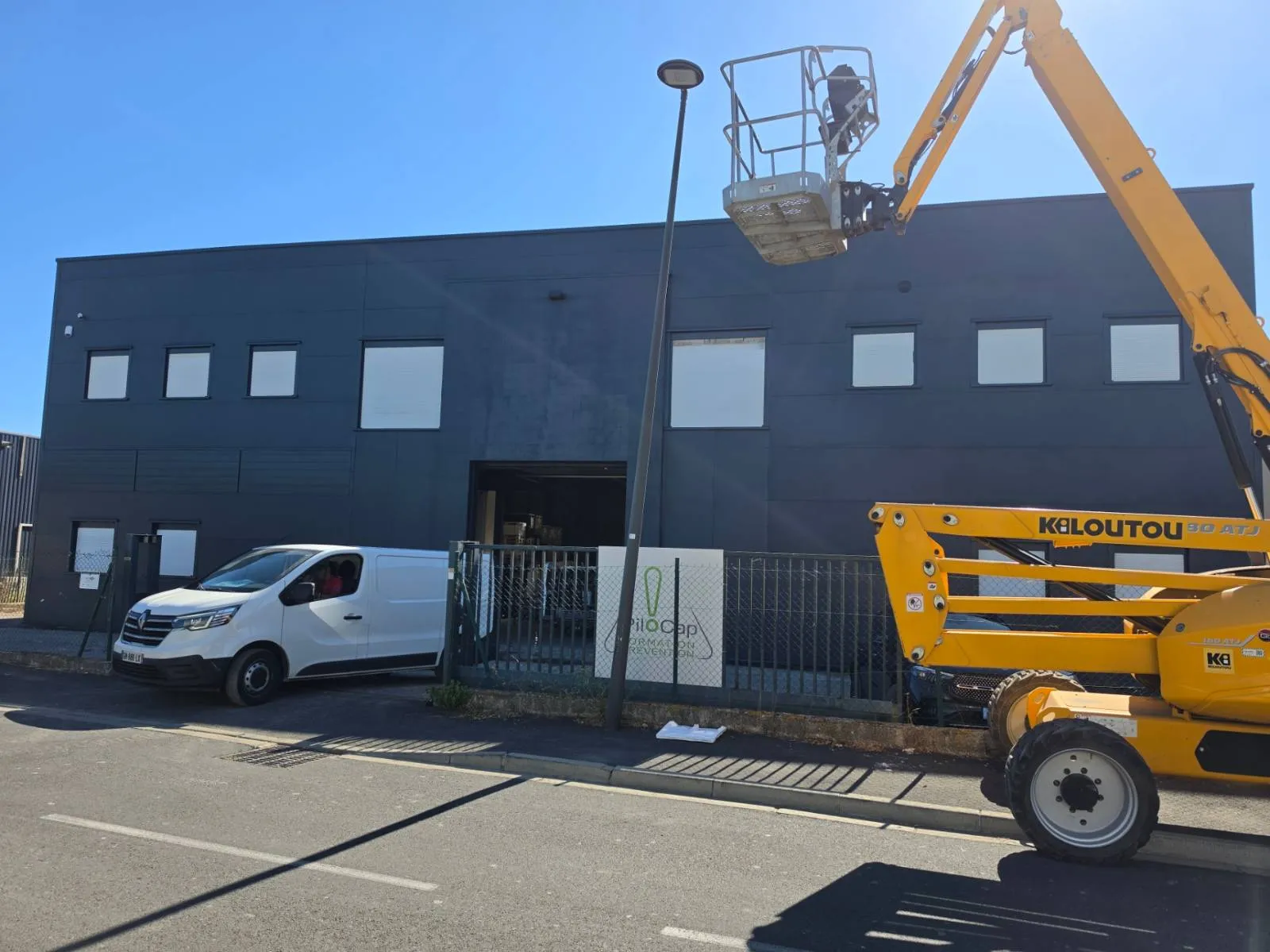 Façade du bâtiment d'activité de Mauguio terminée en RAL 7016 anthracite, nacelle articulée encore en place