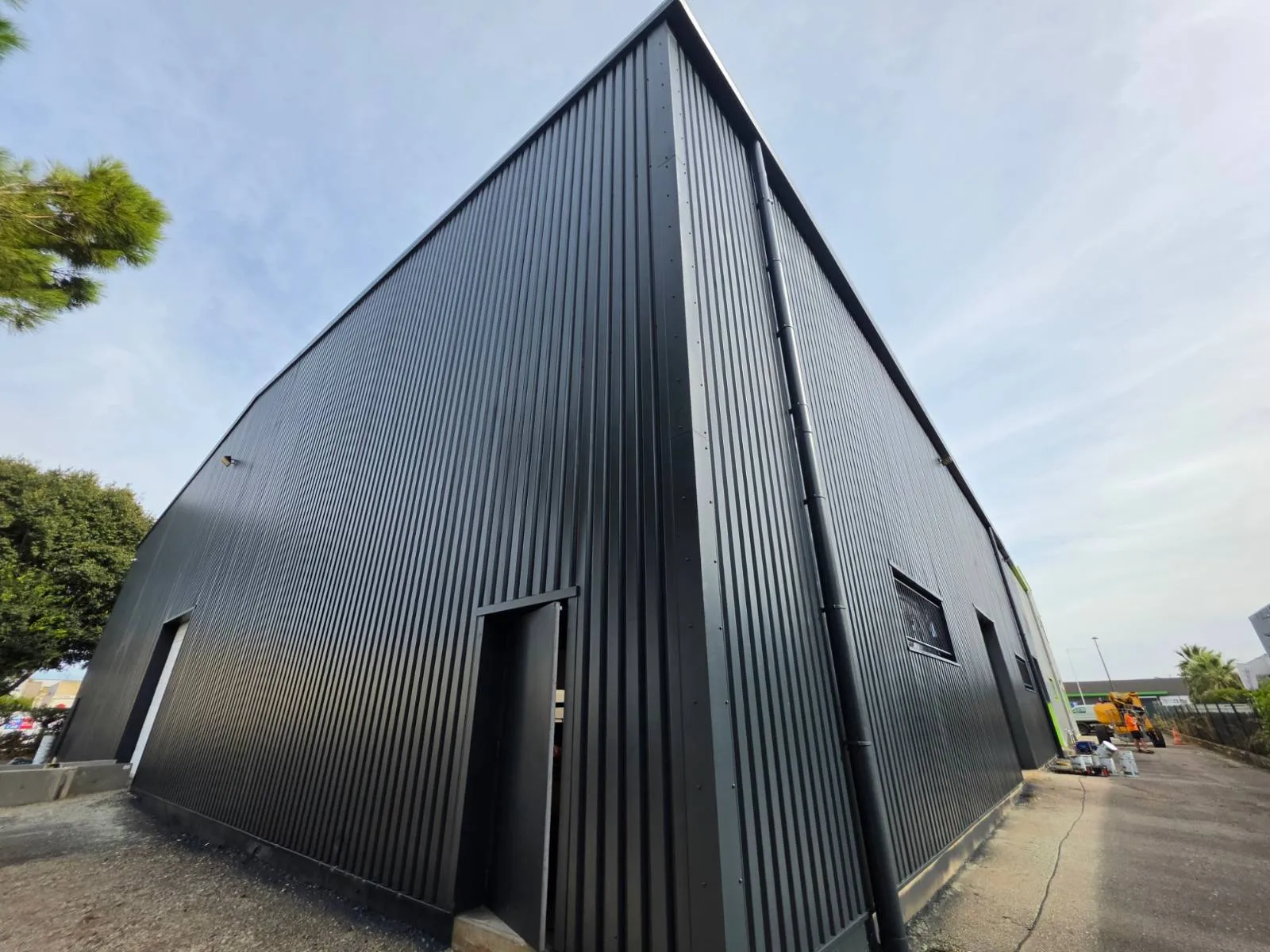 Angle d'un bâtiment d'activité à Mauguio dont le bardage métallique a été repeint en RAL 7016 anthracite par 2KM
