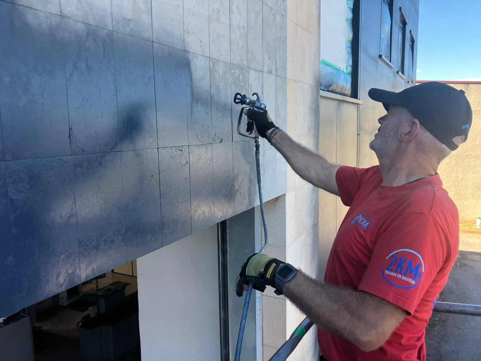 Technicien 2KM appliquant la peinture au pistolet airless sur la façade du bâtiment à Mauguio
