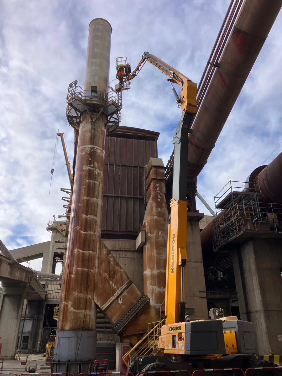 Cheminee en acier carbone fortement corrodee avant intervention sur la cimenterie Lafarge a Port-la-Nouvelle, nacelle telescopique deployee