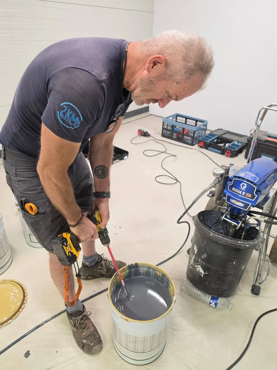 Technicien 2KM preparant la peinture anticorrosion a la pompe airless Graco sur le chantier Flat Cat a Vendres