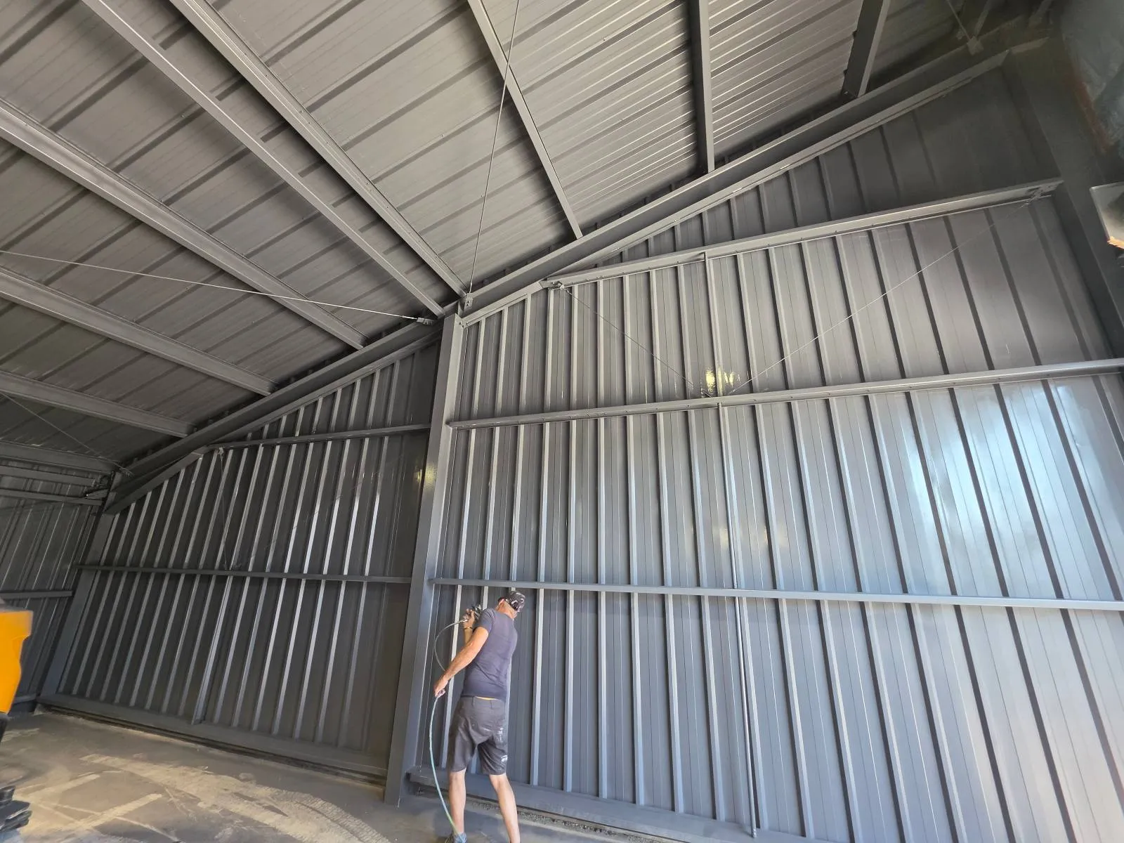 Technicien 2KM appliquant la peinture a l airless sur l ossature metallique du studio Flat Cat a Vendres