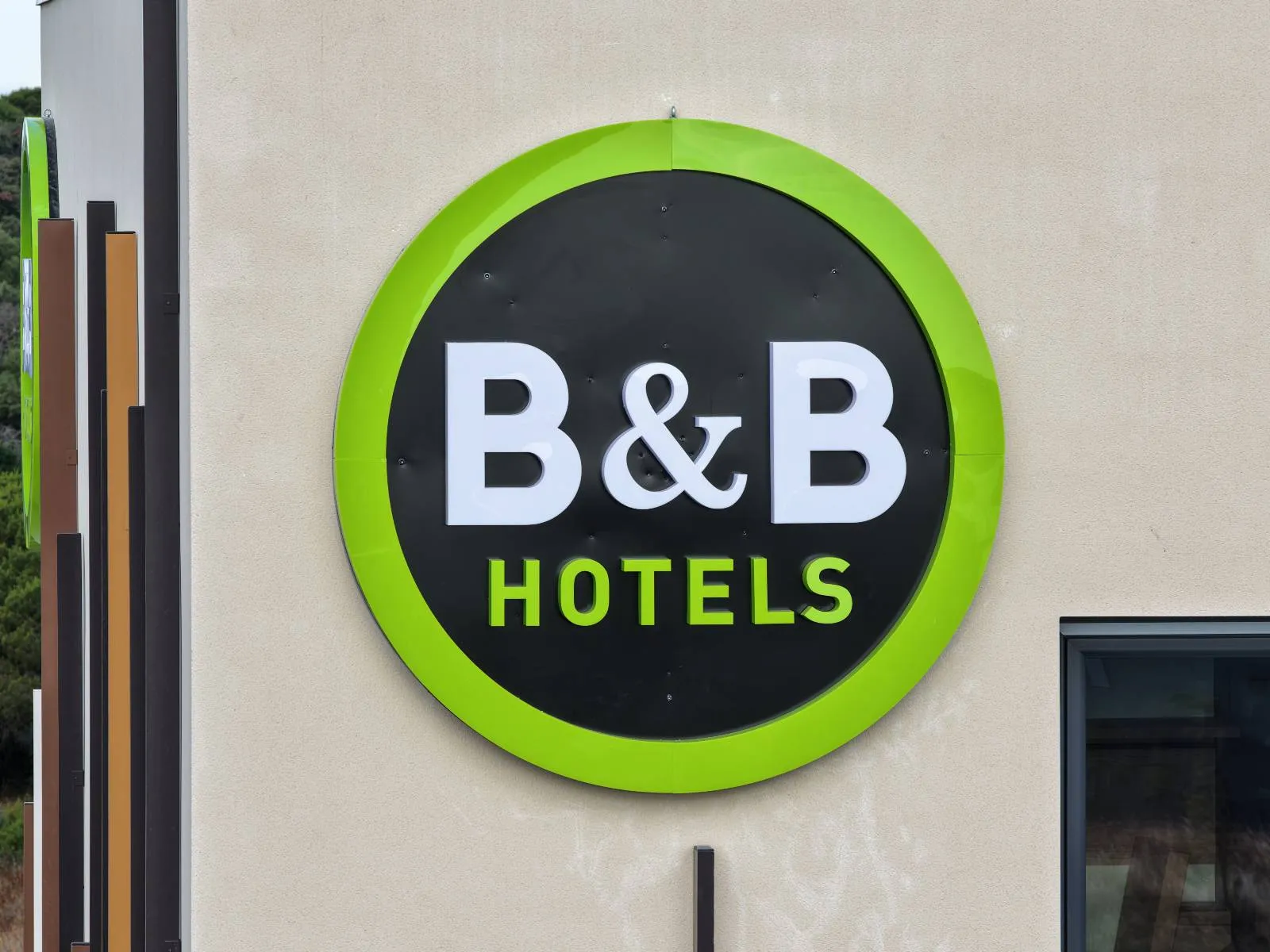 Cordiste 2KM posant une enseigne lumineuse B&B sur la façade de l'hôtel de Bessan