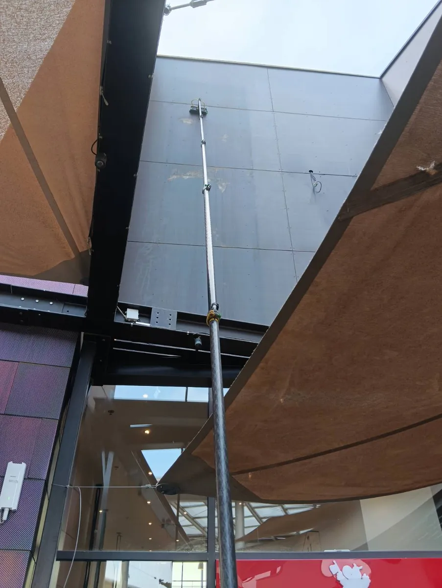Nettoyage de la façade à la perche télescopique alimentée en eau osmosée avant la pose des enseignes