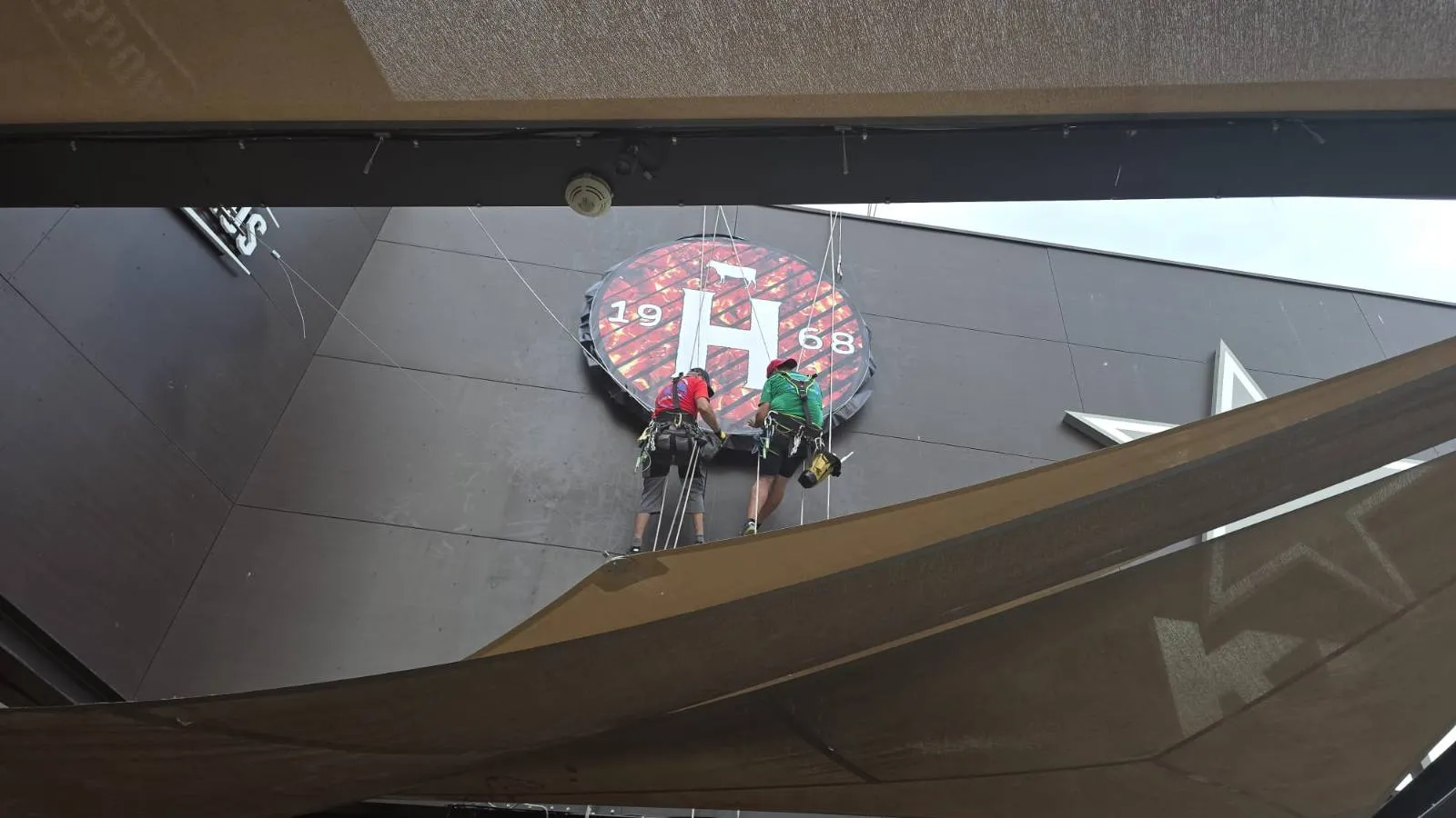 Mise en place et fixation de la toile tendue sur le caisson circulaire de l'enseigne